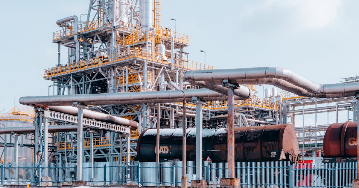 Oil refinery facility with crude tanker wagons under a clear sky