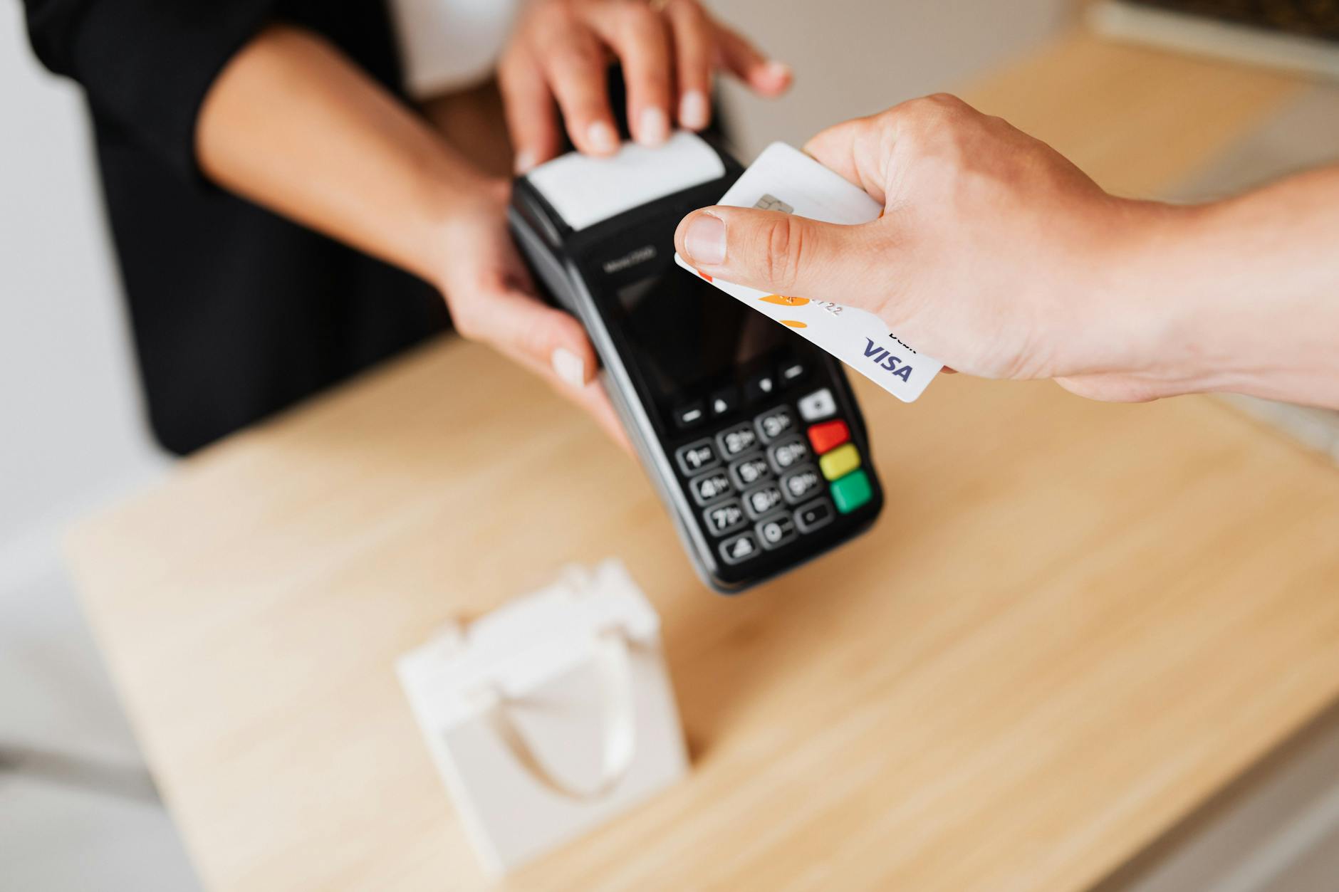Hands using a contactless payment terminal with a credit card indoors